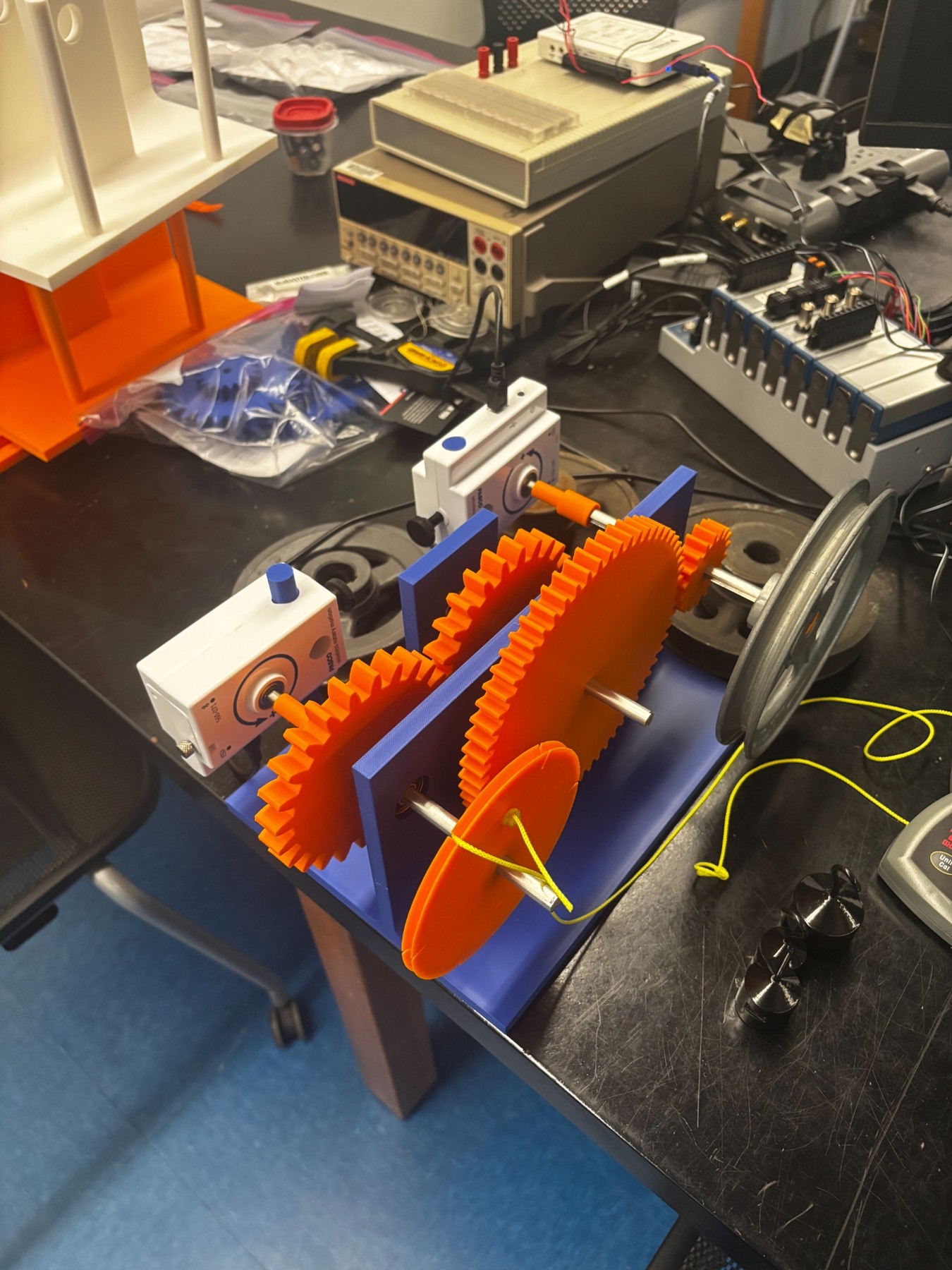 Assembled compound gear-train prototype with PASCO sensors and flywheel.